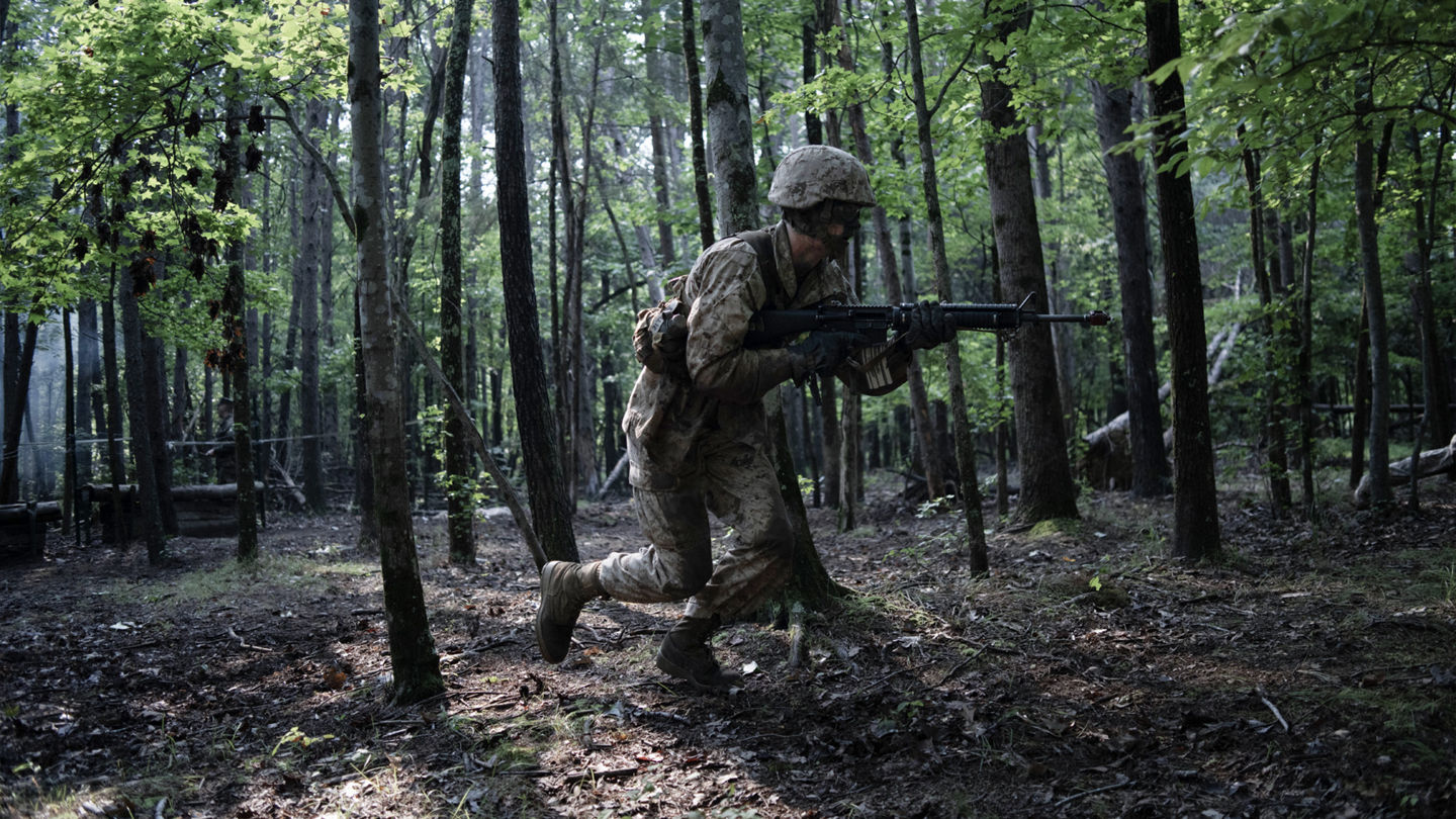 A Marine Officer candidate, with a rifle in hand, sprints through the woods during a training exercise of Officer Candidates School.