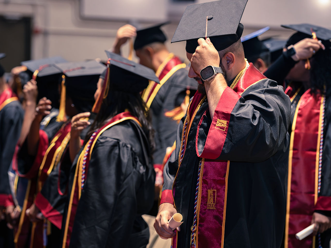Marines in graduation caps and gowns holding diplomas during college commencement ceremony.