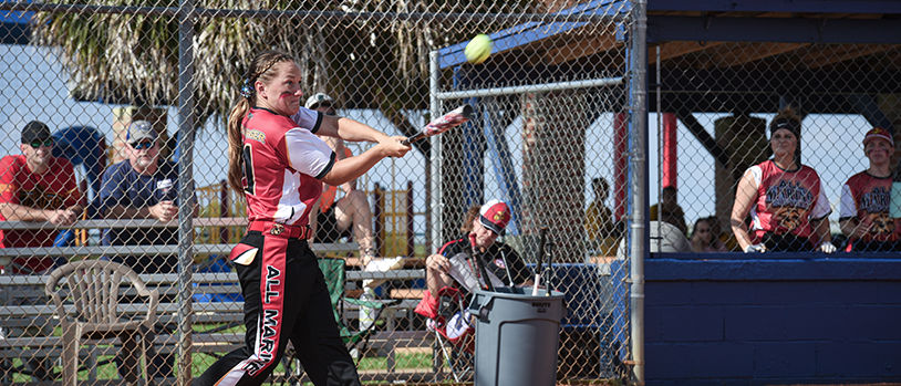 Marine playing softball at base recreation facility with teammates and spectators enjoying athletic competition.