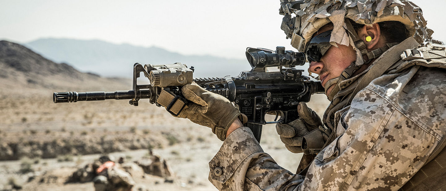 Marine in desert camouflage uniform with optics and rifle during desert terrain training operations.