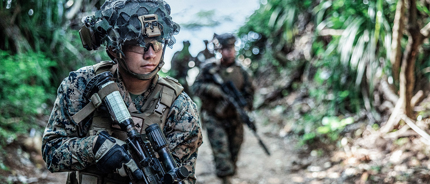 Marine in woodland camouflage uniform with tactical gear and rifle during jungle training exercise.