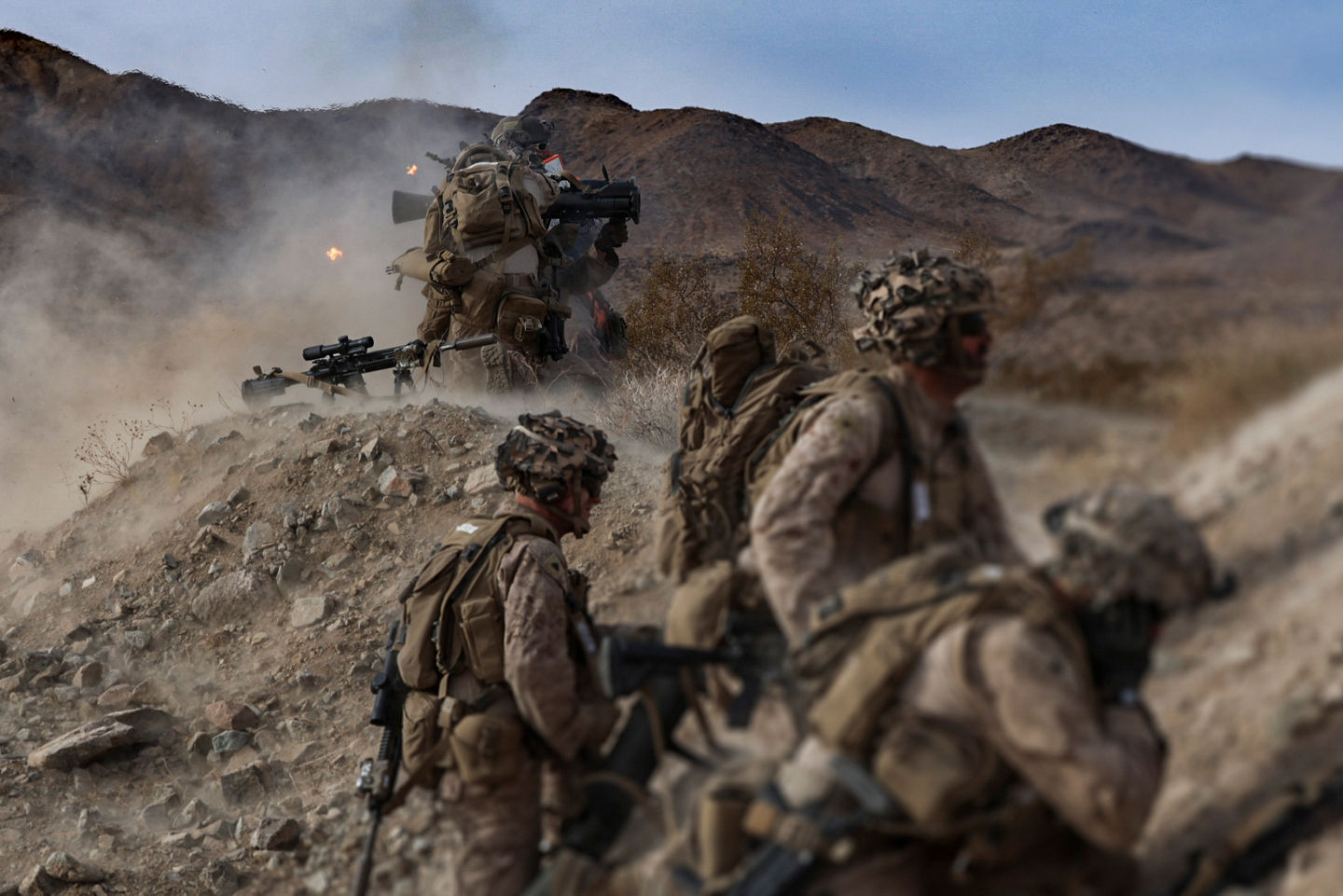 Marines in combat gear exiting V-22 Osprey aircraft during field training exercise in grassy terrain.