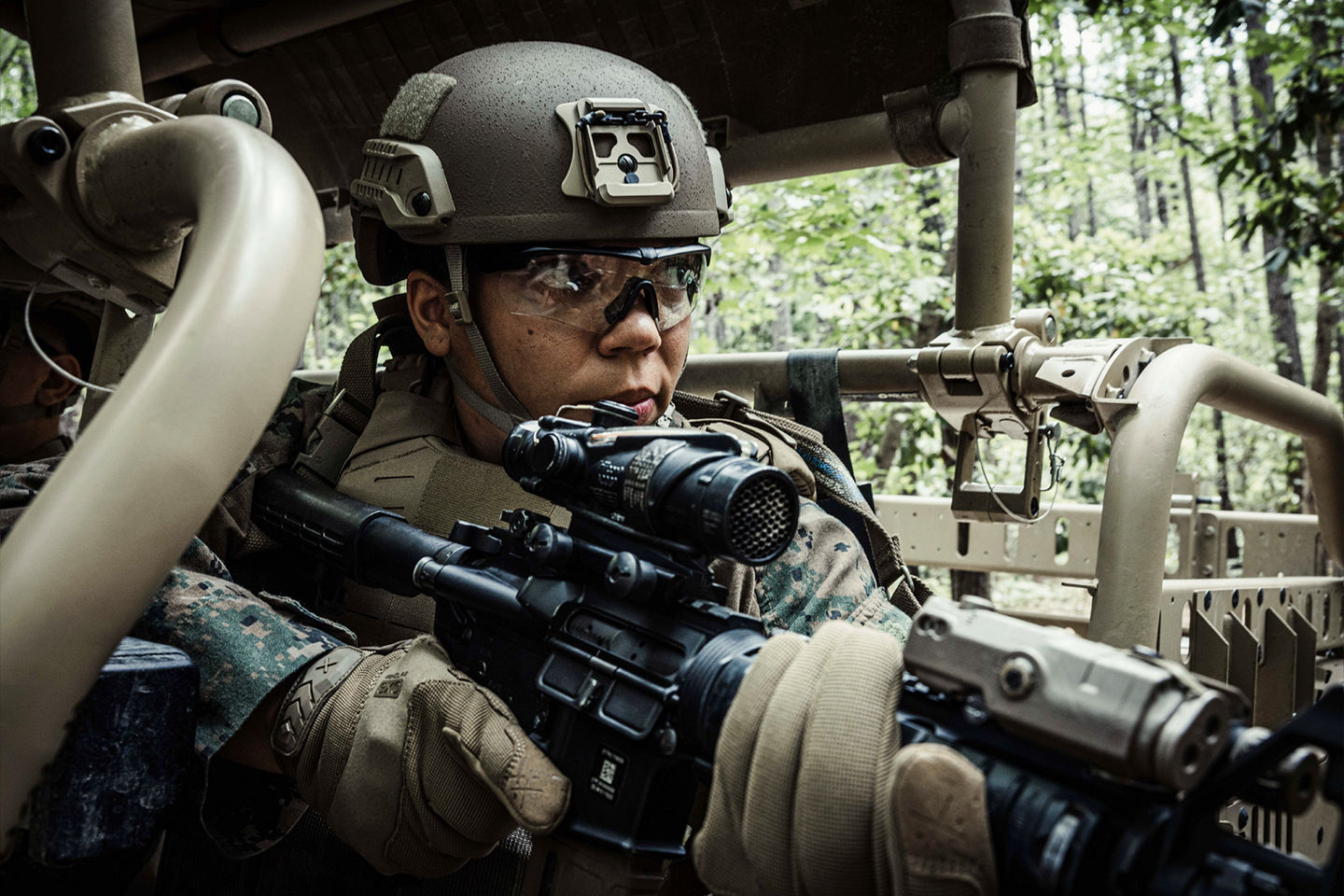 Marine in tactical helmet with advanced optics and rifle demonstrating focused mindset during vehicle-based training exercise.