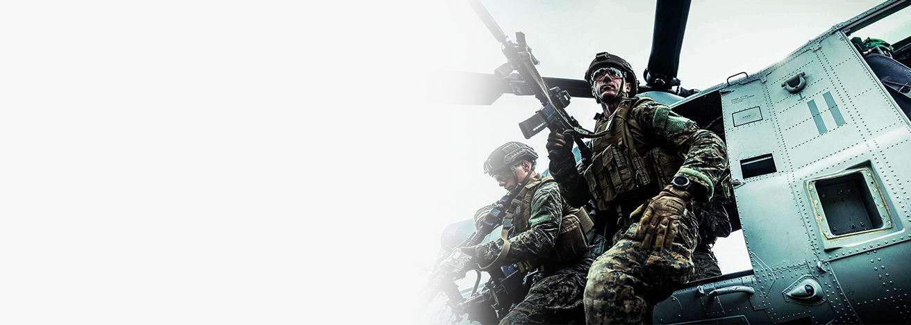 Marines in tactical gear with rifles conducting helicopter insertion training during air assault operations exercise.
