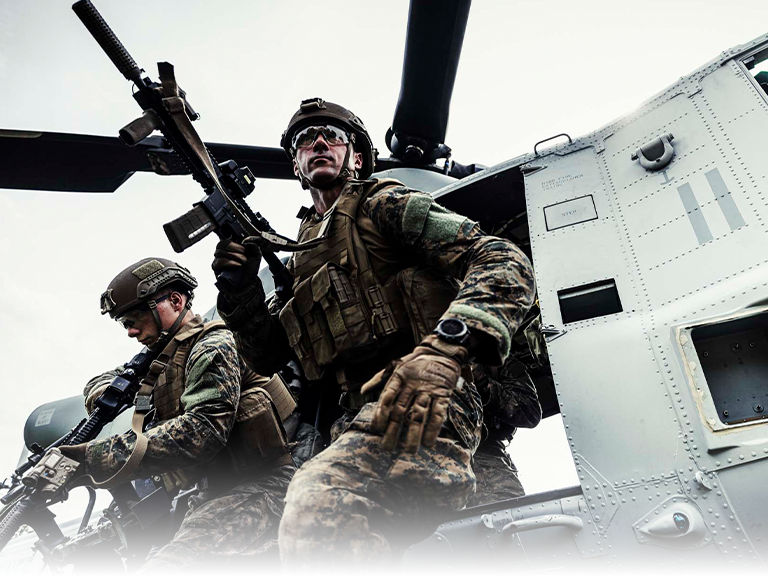 Marines in tactical gear with rifles conducting helicopter insertion training during air assault operations exercise.