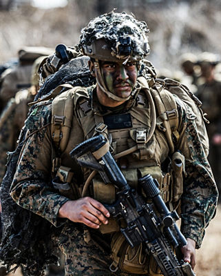 Marine carrying shoulder-fired missile launcher and rifle during pre-flight operations in South Korea.