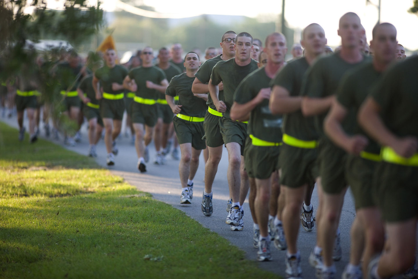 A large group of male recruits jog in physical training uniforms during recruit training.