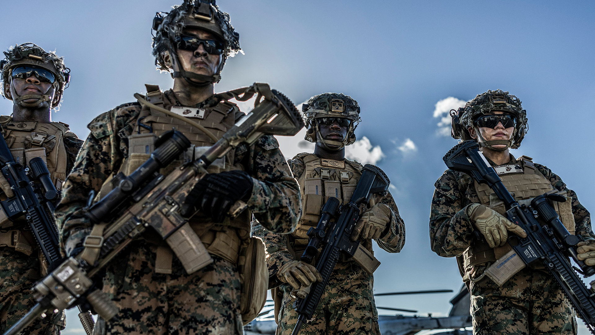 Marine officers in full tactical gear with rifles and communications equipment stand ready during combat training exercise.