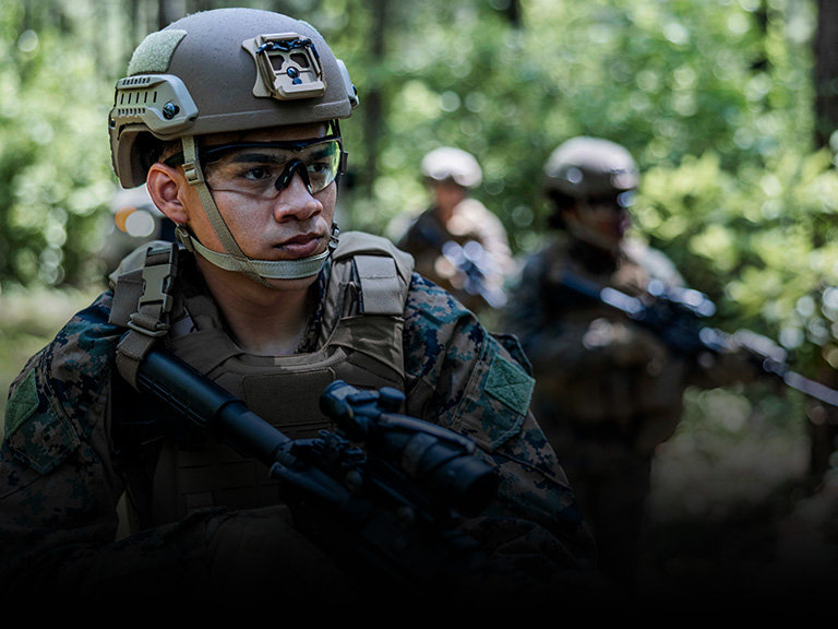 Marine in combat gear and helmet demonstrating tactical roles and specialties within Marine Corps ranks.