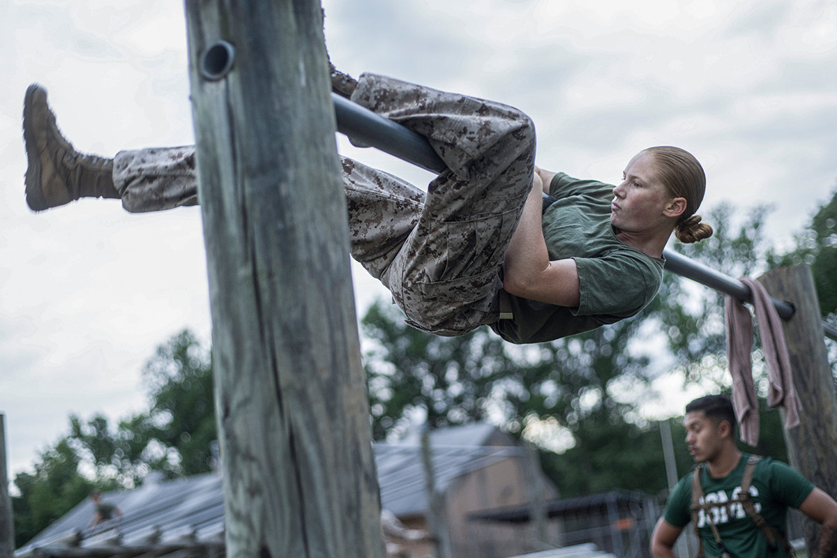 Marine officer candidate climbs vertical obstacle during physical fitness training on obstacle course at Officer Candidates School.