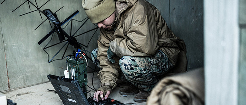 Marine operating advanced communications equipment and laptop during field operations in South Korea.