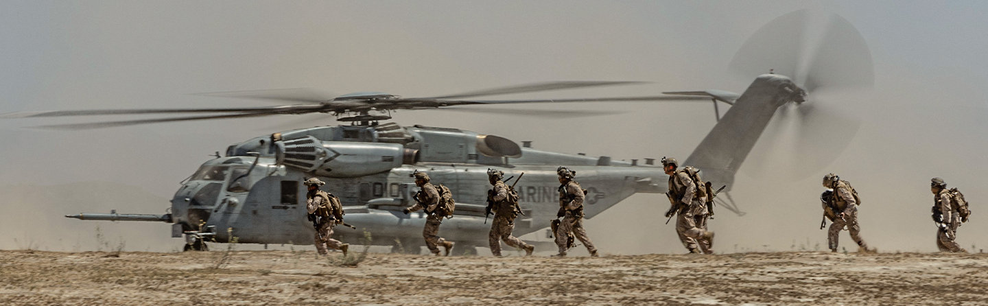 Marines disembark from CH-53 Sea Stallion helicopter during air-ground task force training operation in desert terrain.