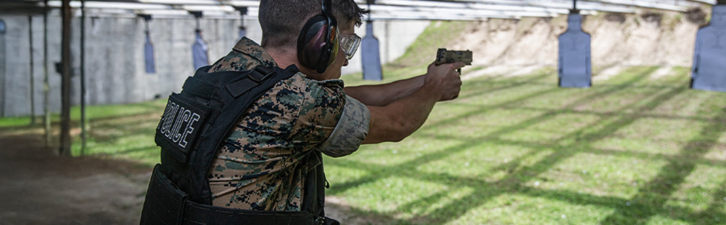 A law enforcement Marine practices his marksmanship at a firing range as he fires a pistol at a target.