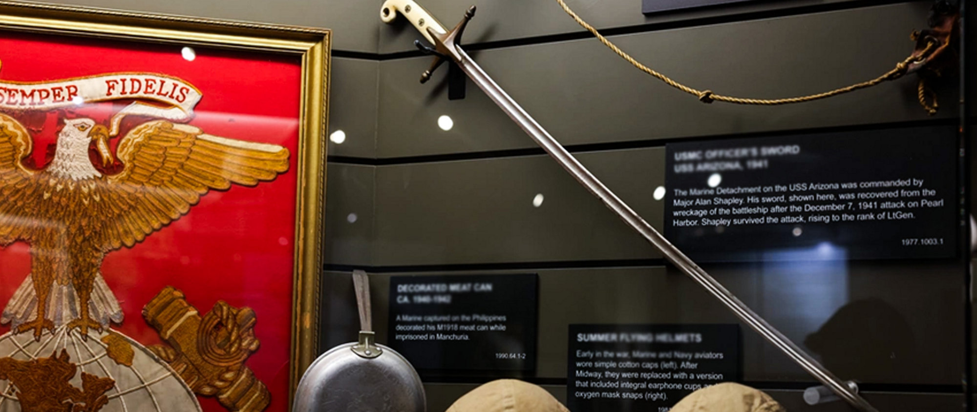 A group of Marines run across a grassy field, carrying the US flag and a large red Marine Corps flag featuring the eagle, globe, and anchor.