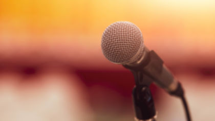 Close-up view of a microphone with a crowd in the background.