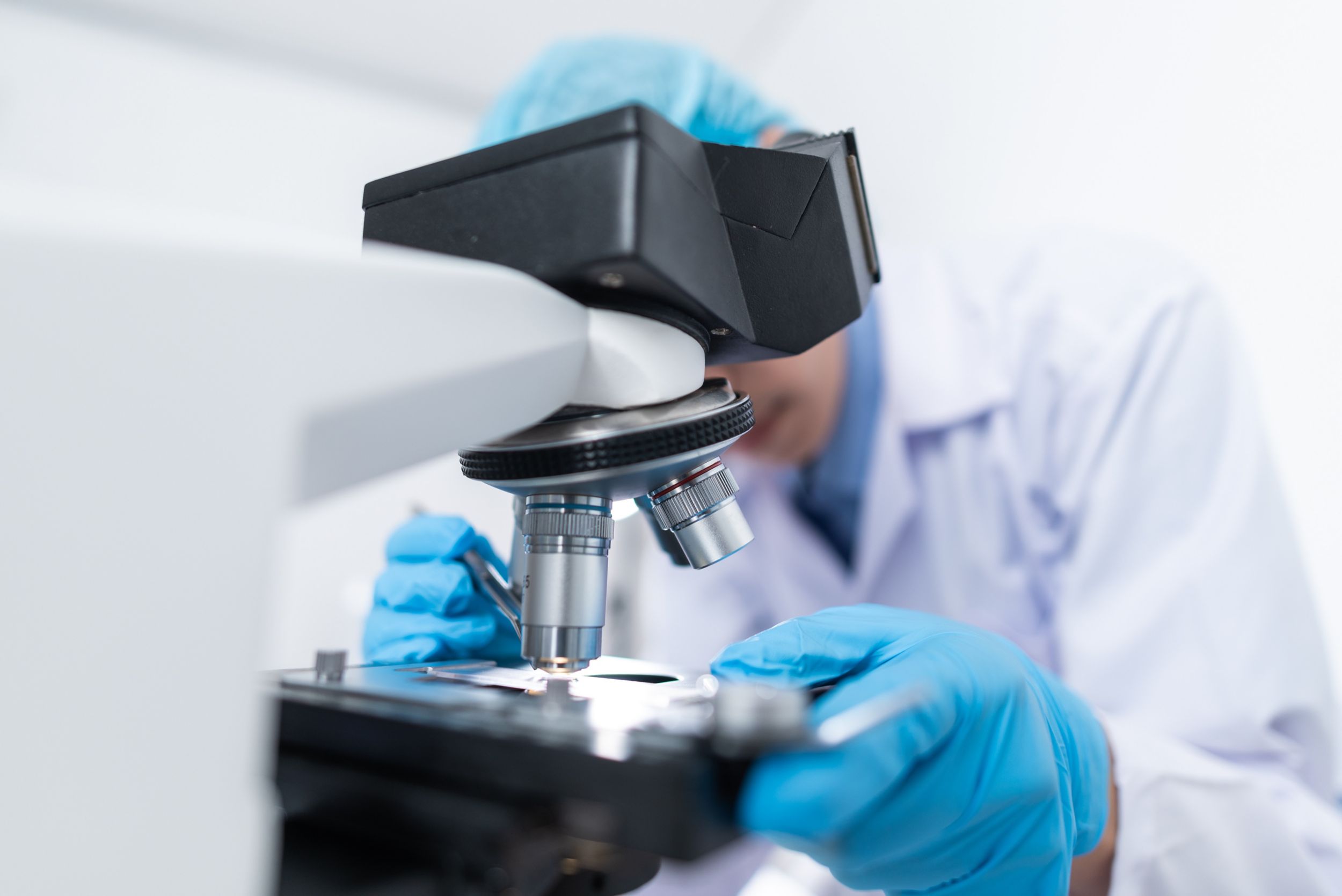 lab technician looking through microscope