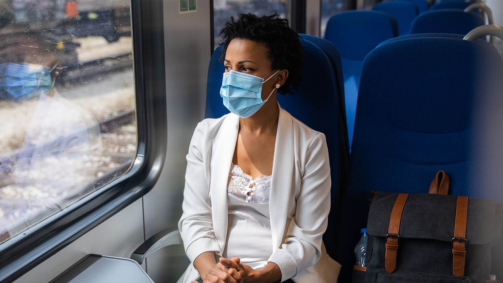 Woman riding on train wearing a mask