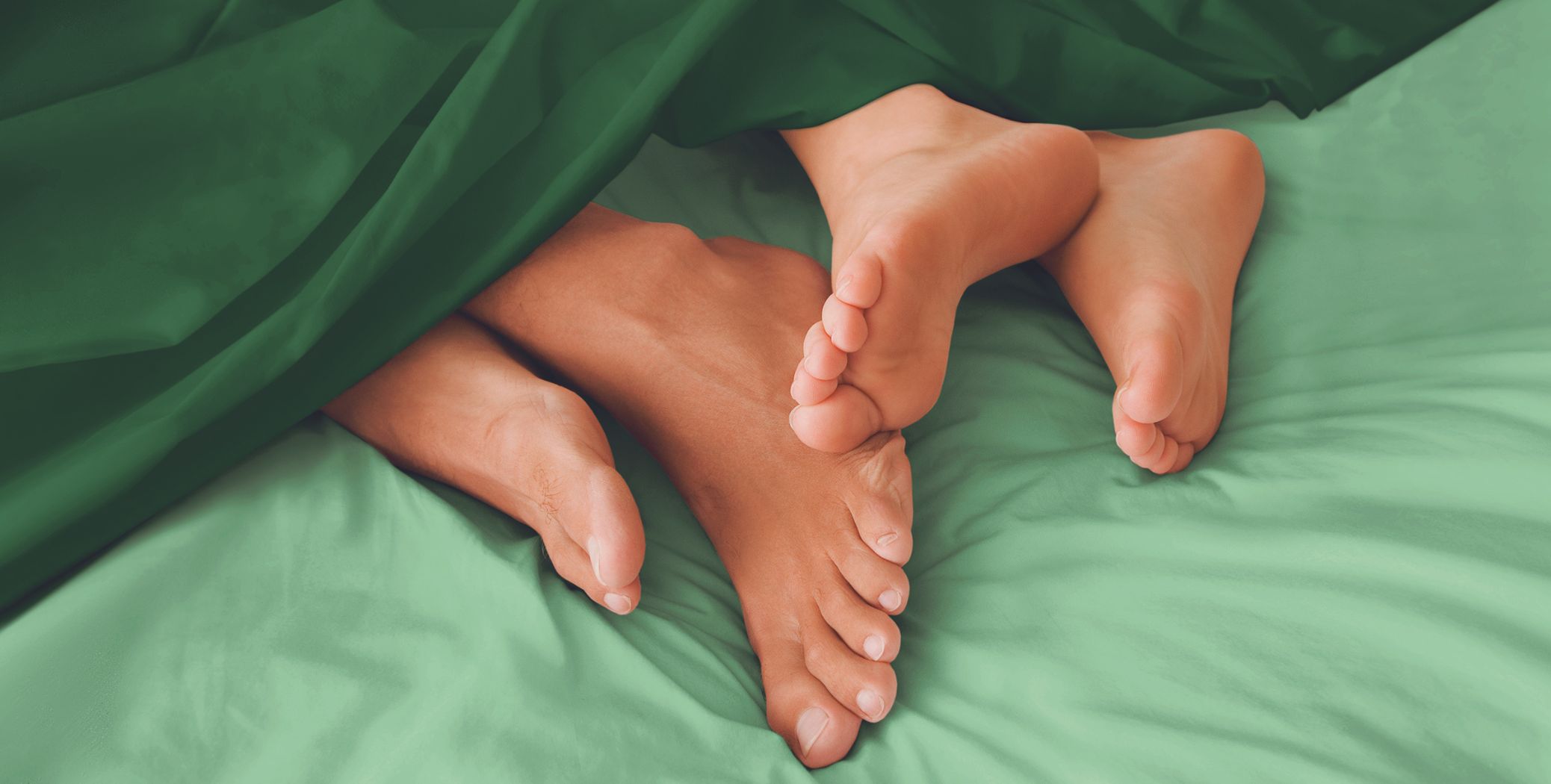Feet coming out of sheets in a bed