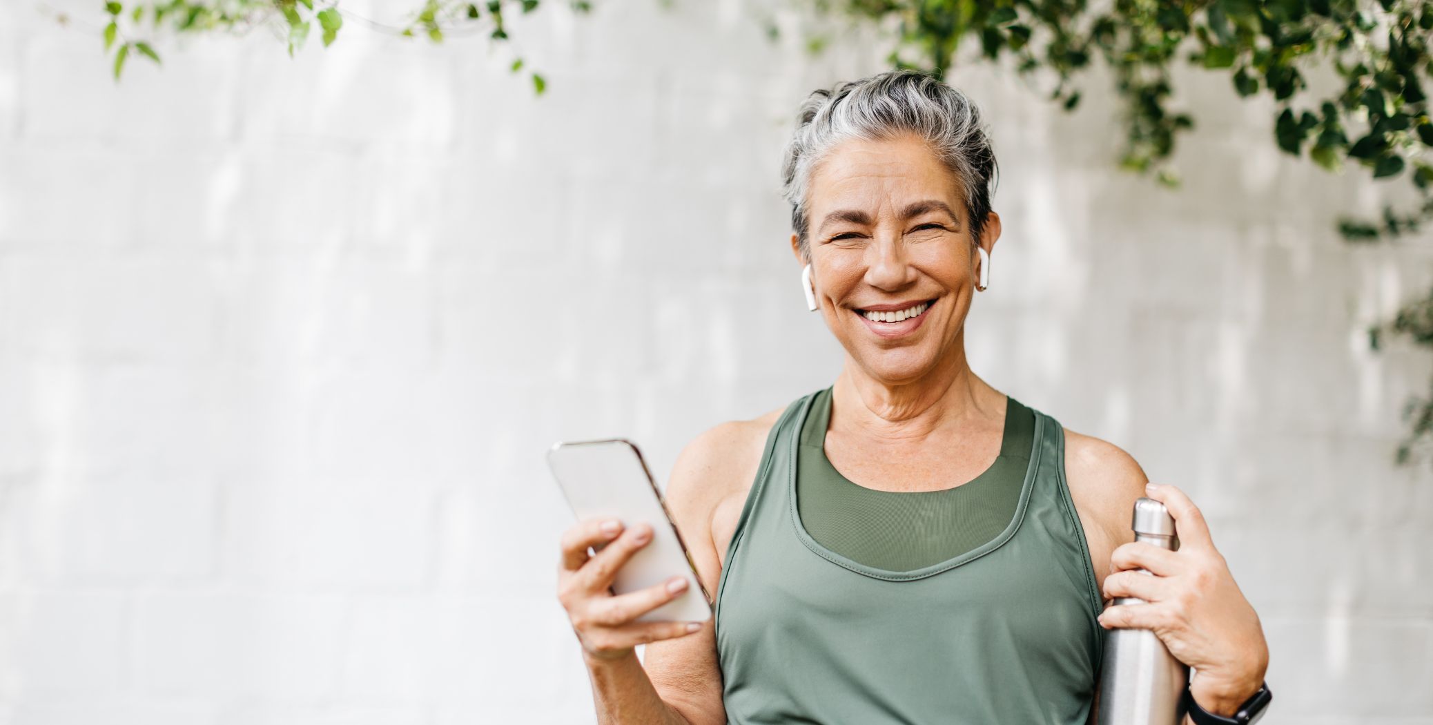 Woman smiling holding a water bottle and cell phone