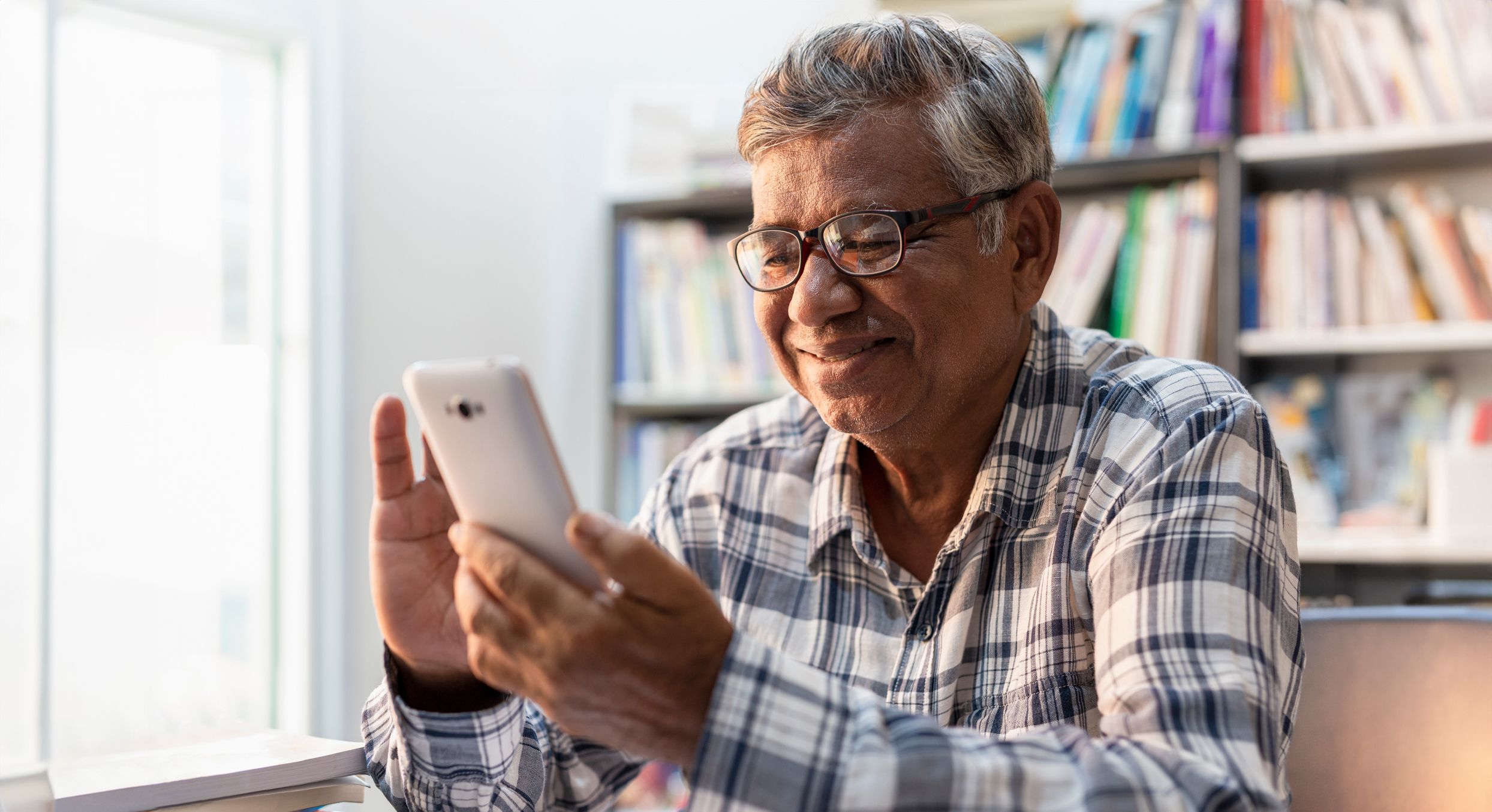 Happy elderly Asian using smartphone at home