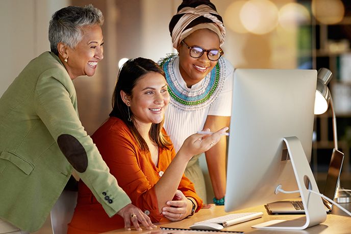 Team of business women looking at a computer in collaboration