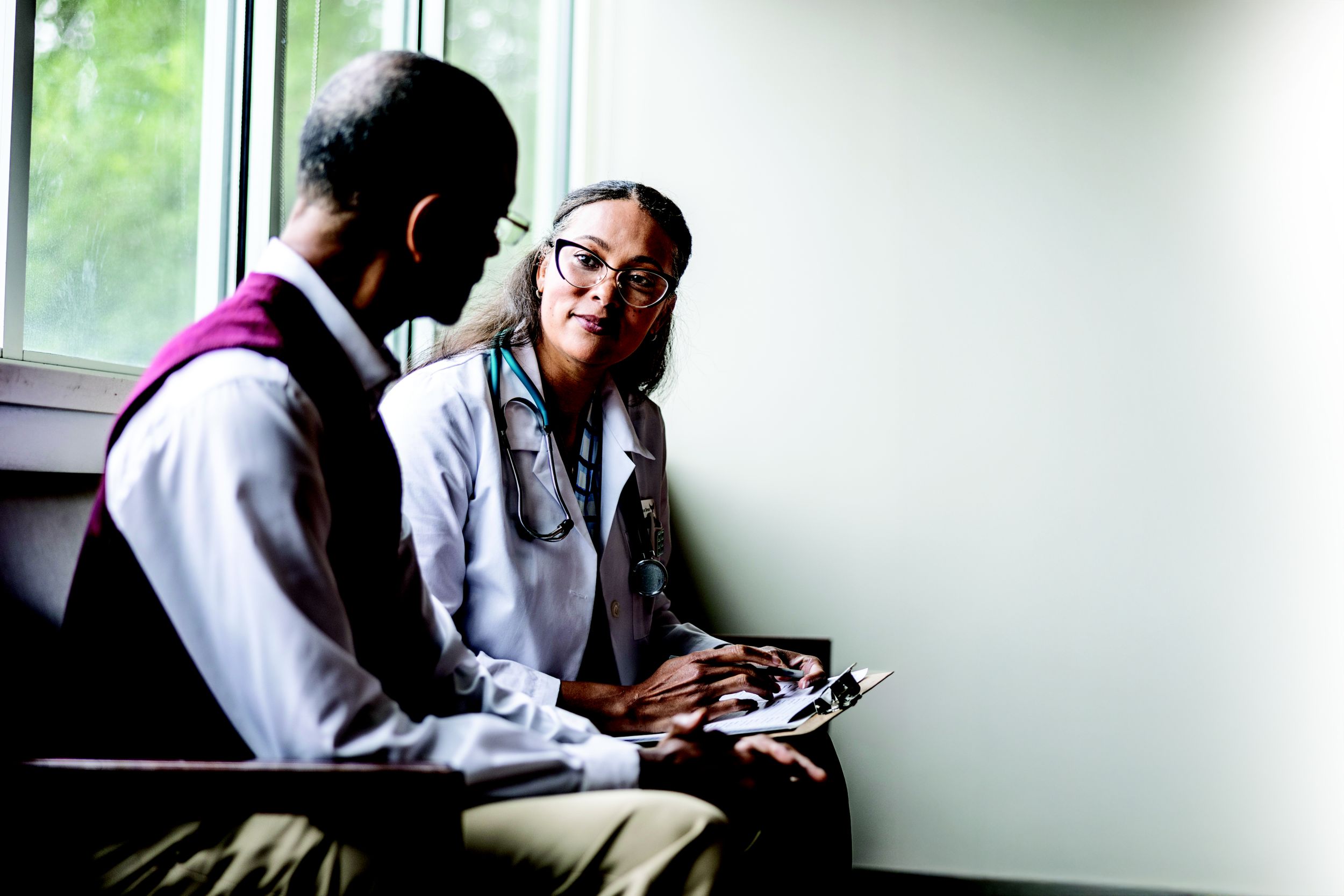 Female doctor talking with senior man in waiting room