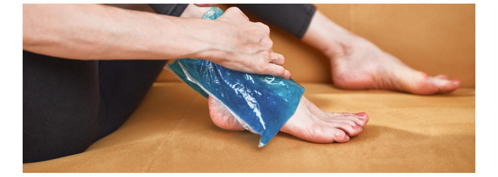 Woman holding an ice gel pack over an ankle injury.