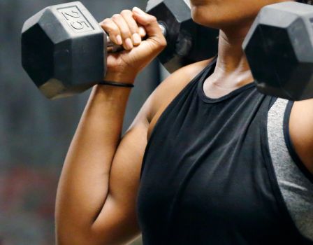 Fit, young African American woman working out with hand weights.