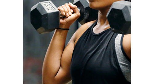 Fit, young African American woman working out with hand weights.