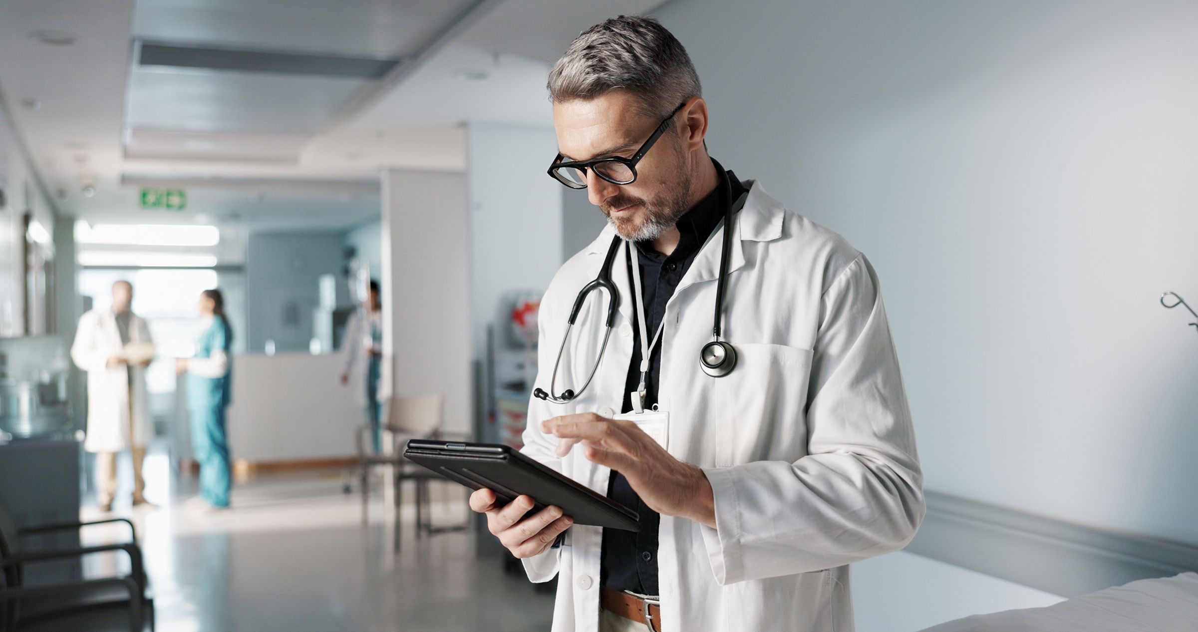 Doctor, hospital and tablet for medical information, typing and management of online charts or results. Healthcare worker, man or expert with digital technology for health services, planning and data
