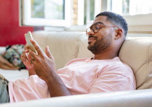 Man on couch scrolling on cell phone