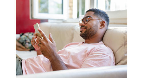 Man on couch scrolling on cell phone