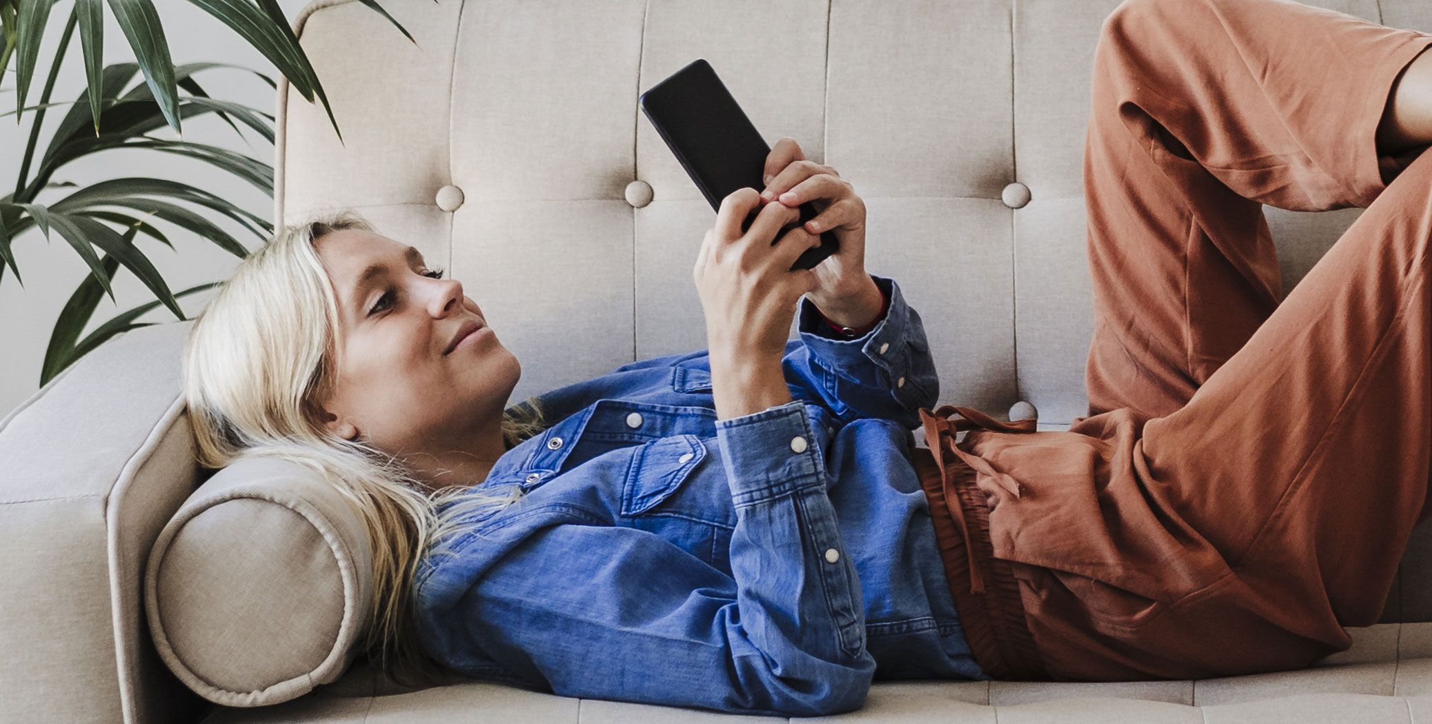 Woman lsying on the couch on her phone
