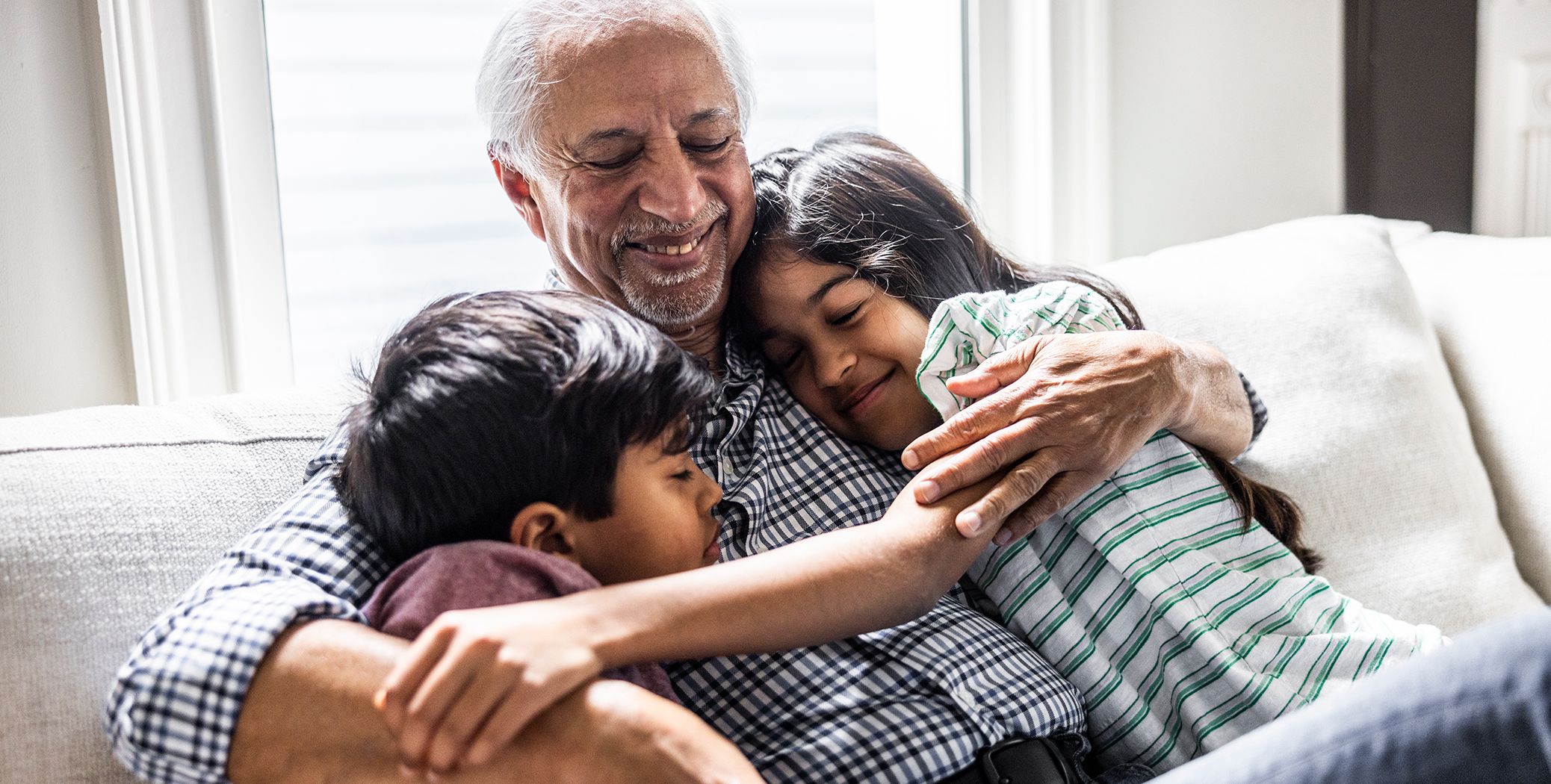 Man hugging 2 kids on couch