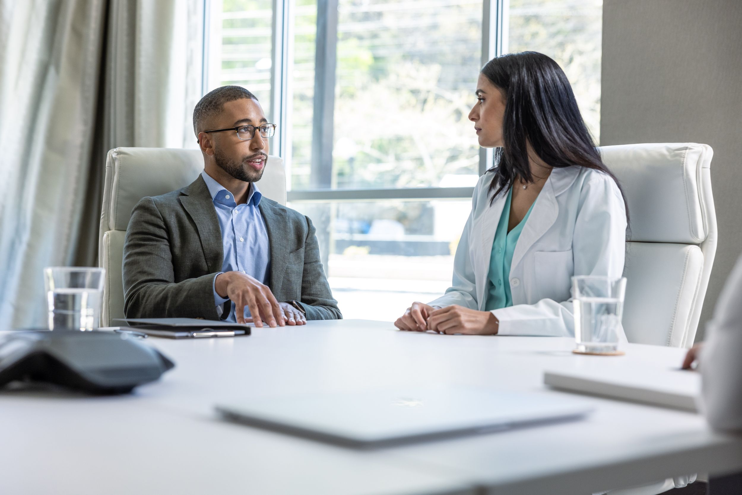 physician sitting at a table talking to a patient