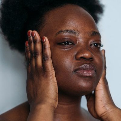 Black woman with concerned expression pressing her palms to her head