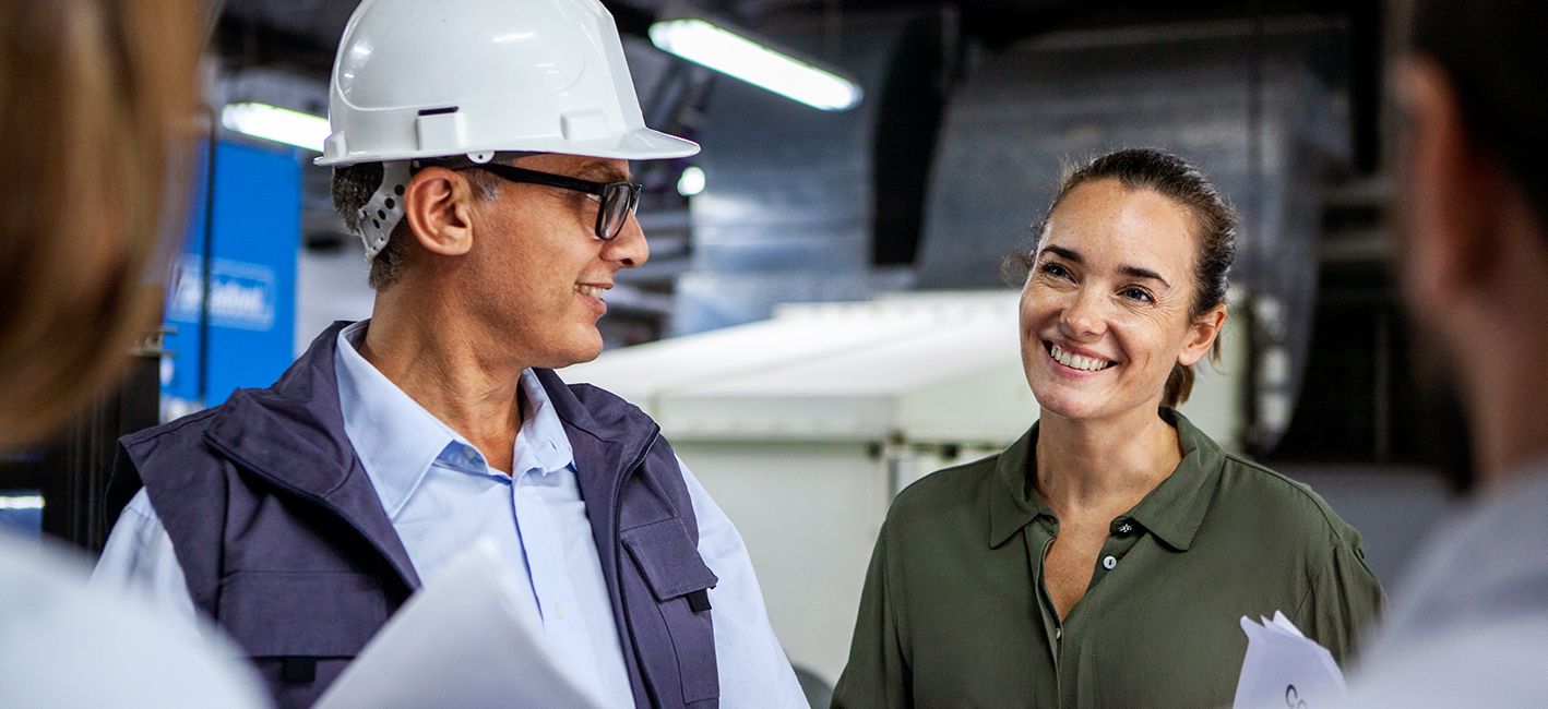 Man in hard hat and woman in factory setting