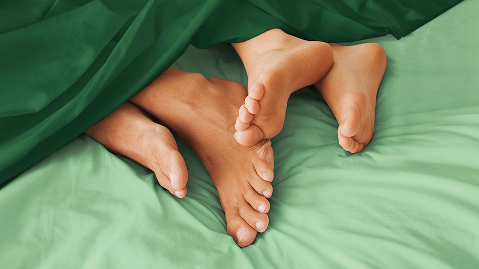 Two pairs of feet on a bed