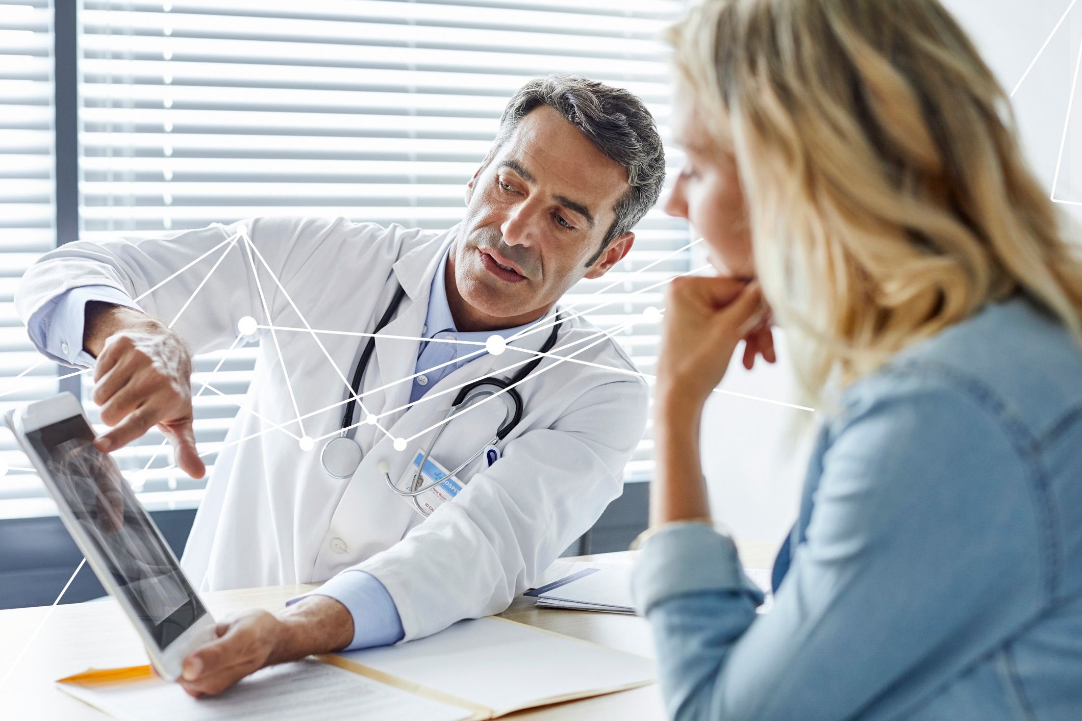 Doctor showing patient a tablet with Quest Advanced lines running through image