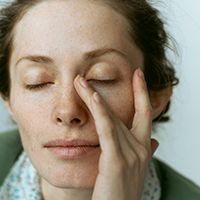 Woman with hand on her head showing signs of a headache