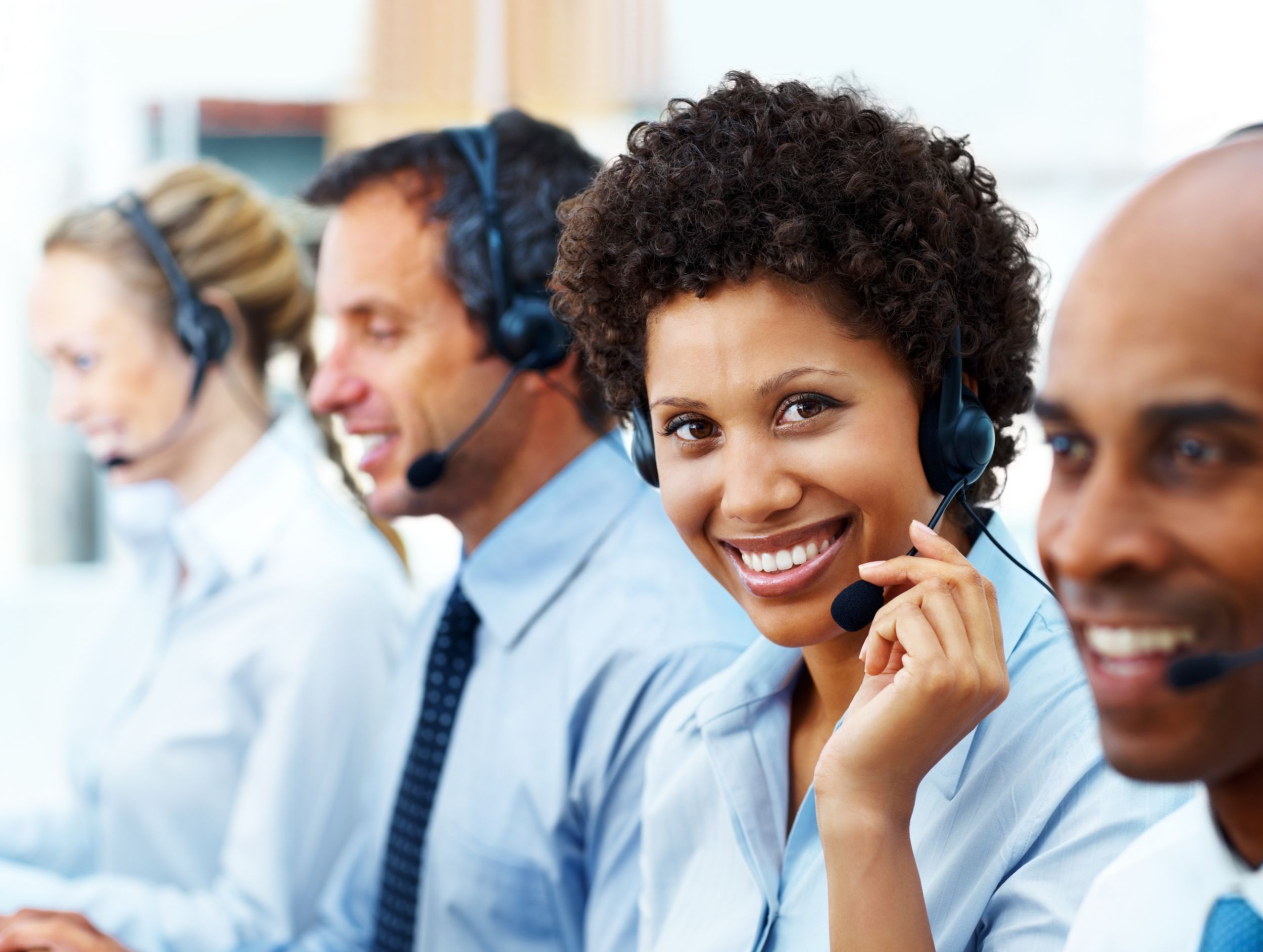 Portrait of a female telephonist working with her colleagues and smiling in office