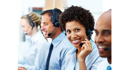 Portrait of a female telephonist working with her colleagues and smiling in office
