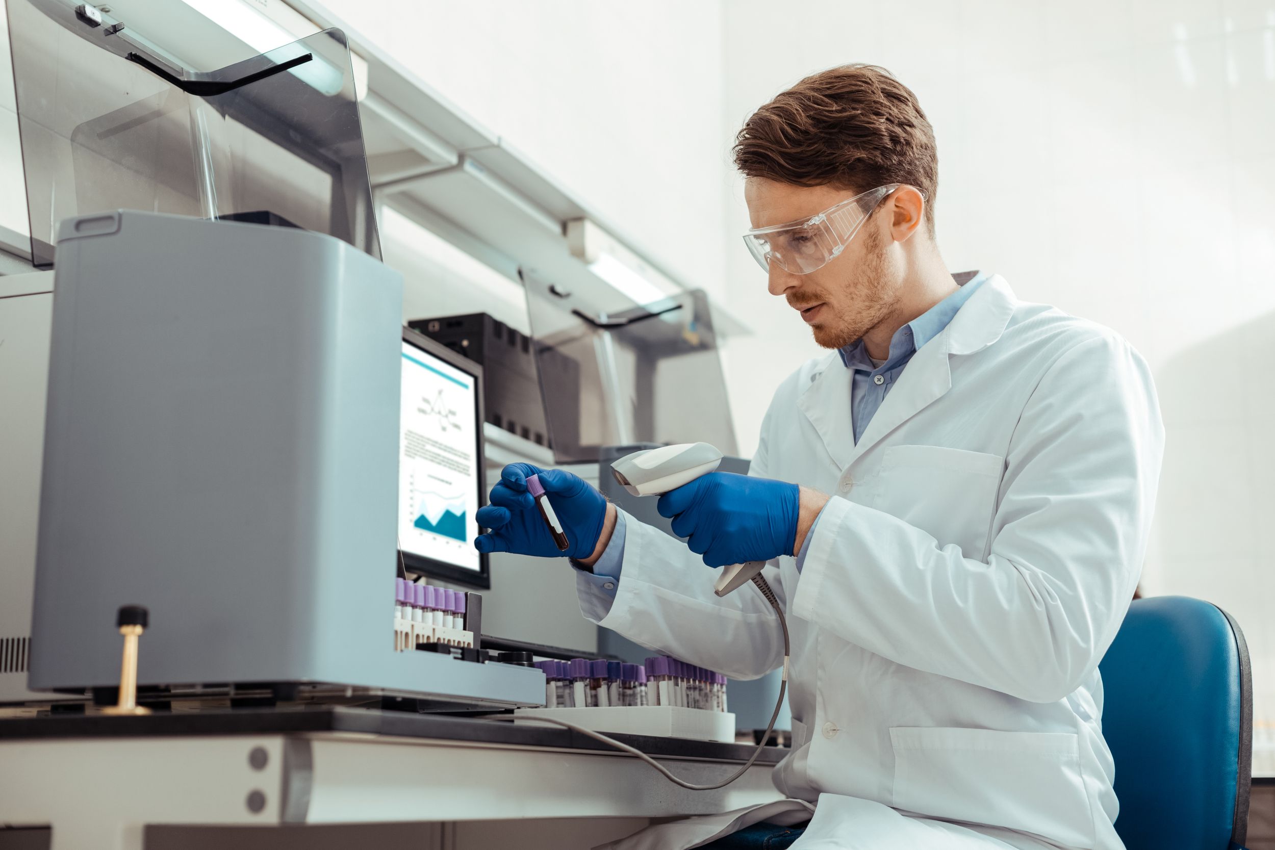 Lab technician scanning a test tube label while conducting a blood test