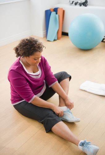 African American woman sitting on floor putting on shoes