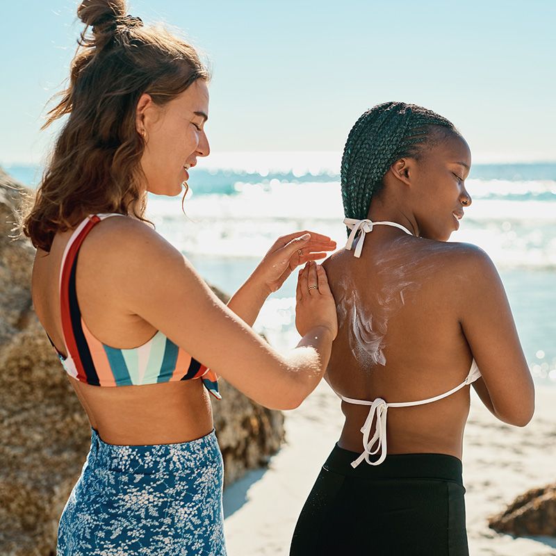girls applying sun screen on beach