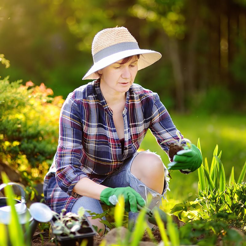 woman gardening wearing hat and long sleeves