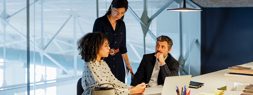 2 women and 1 man discussing work at a conference table