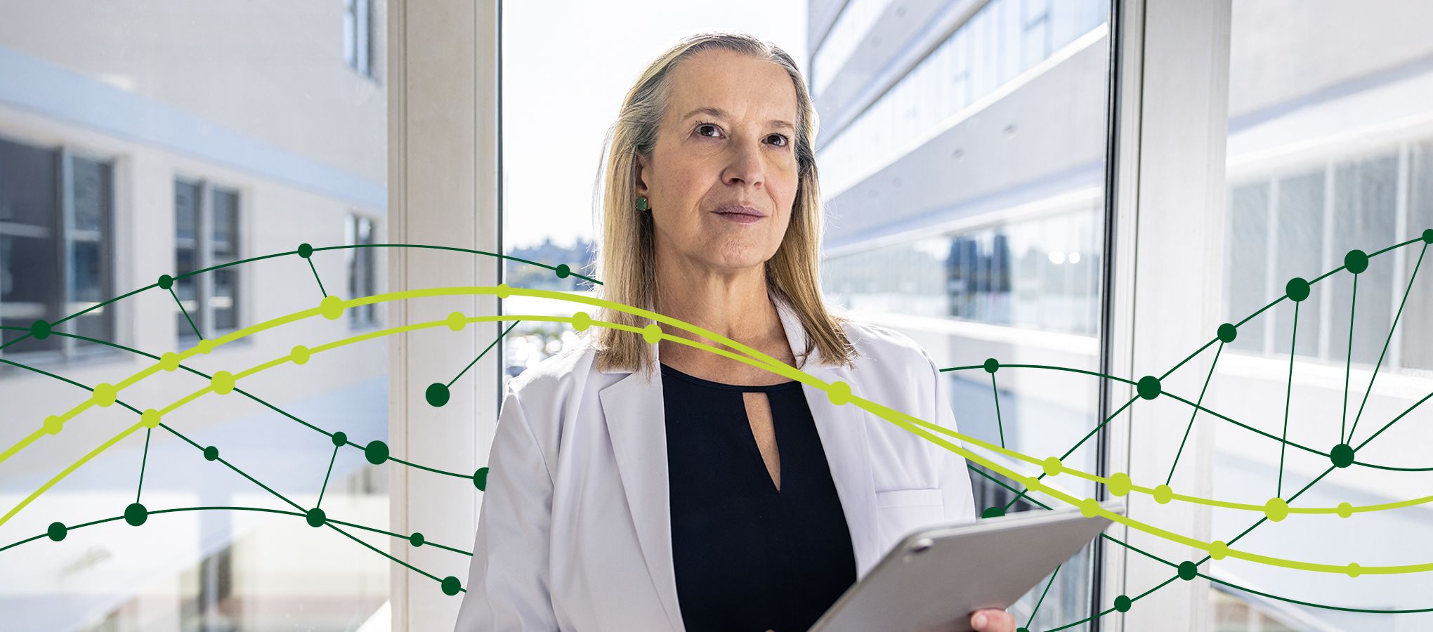 woman in lab coat holding tablet with DNA strand graphic