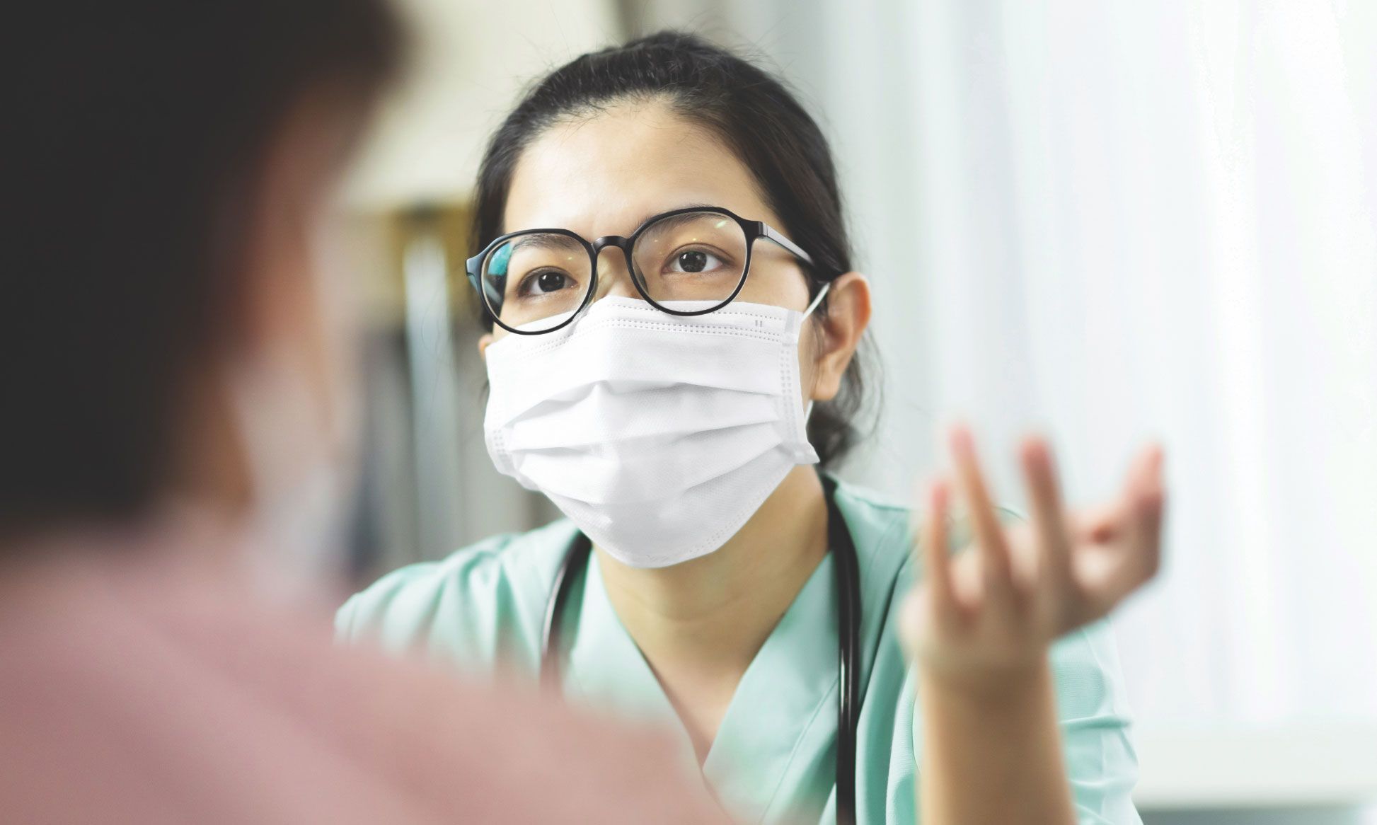 masked doctor speaking to patient