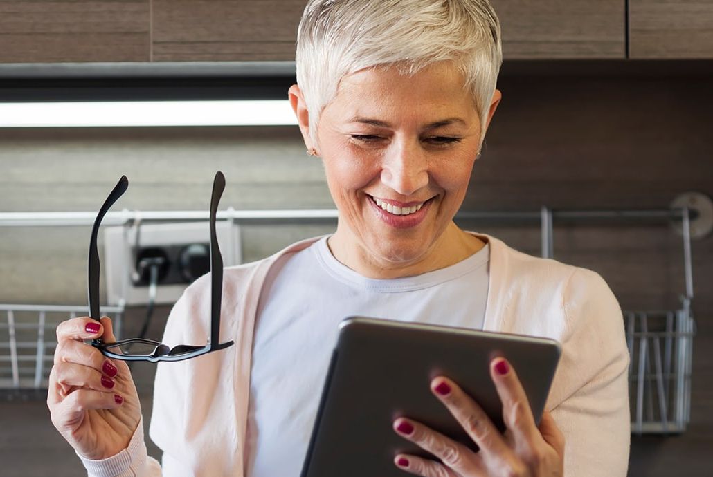 Woman taking off glasses to look at device